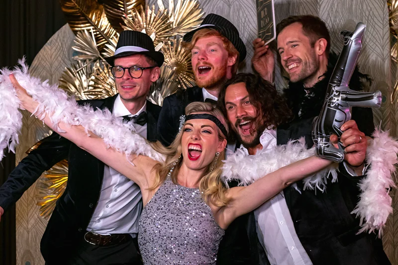 Cinq collègues en tenue de soirée posent devant un photobooth d'entreprise