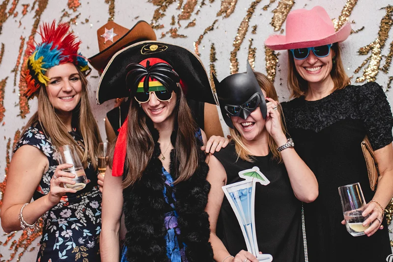 Quatre femmes déguisées avec accessoires devant un photobooth lors d'une soirée privée